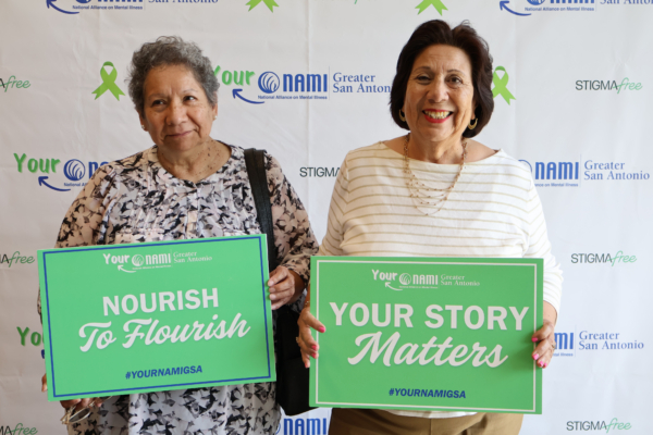 Two women holding mental health support signs at a NAMI Greater San Antonio event