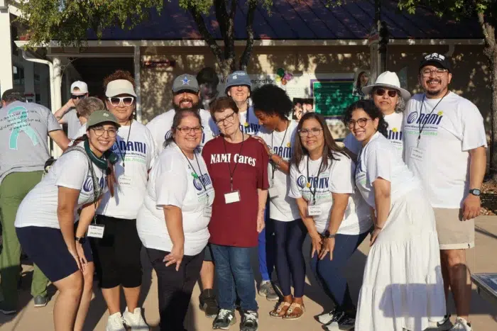 Group of people wearing matching shirts at an outdoor event smiling at the camera