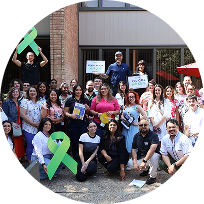 Group of people smiling outdoors holding support signs with mental health awareness ribbons