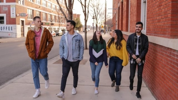 Group of friends walking and laughing on a city street on a sunny day