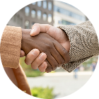 Two people shaking hands outside modern office building