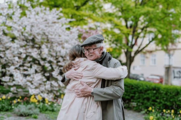 Elderly man and woman hugging in a spring garden with blooming trees and flowers