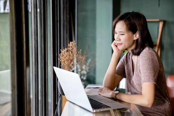 Woman smiling while using a laptop in a cafe