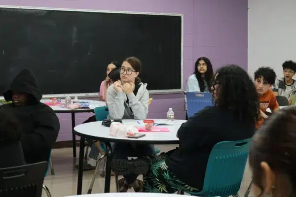Students attentively listening in a classroom with a chalkboard in the background