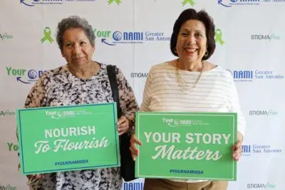 Two women holding supportive mental health signs at a NAMI Greater San Antonio event