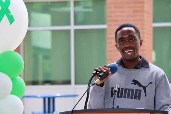 Man speaking at a podium with balloons in the background