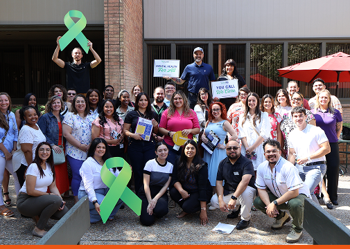 Group of people posing outdoors with green ribbons and awareness signs