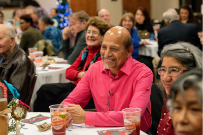 People enjoying a festive gathering with drinks at a decorated event hall