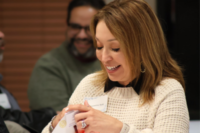 Woman smiling while reading a card at a social event indoors