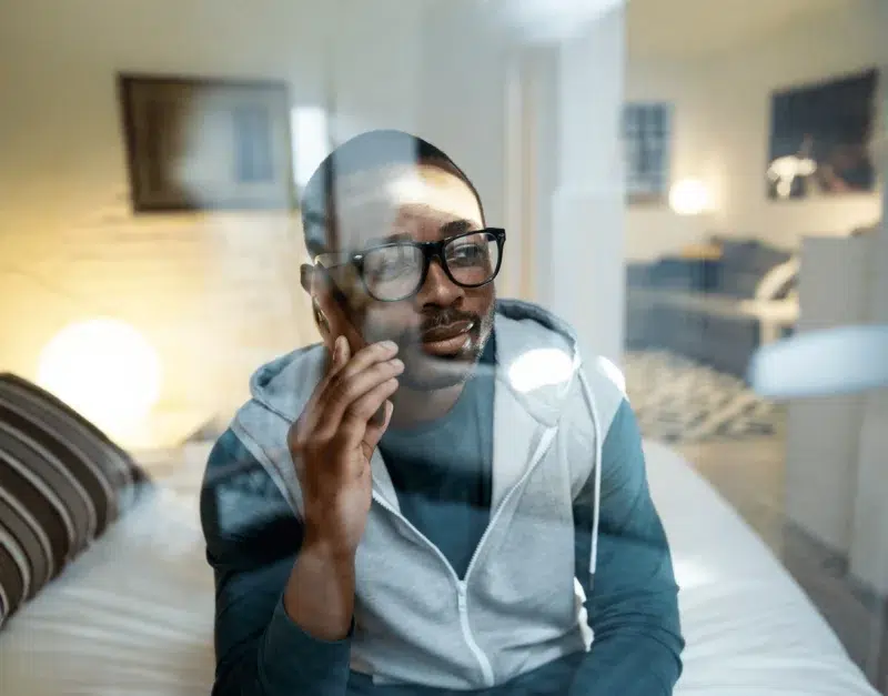 Man wearing glasses talking on smartphone indoors